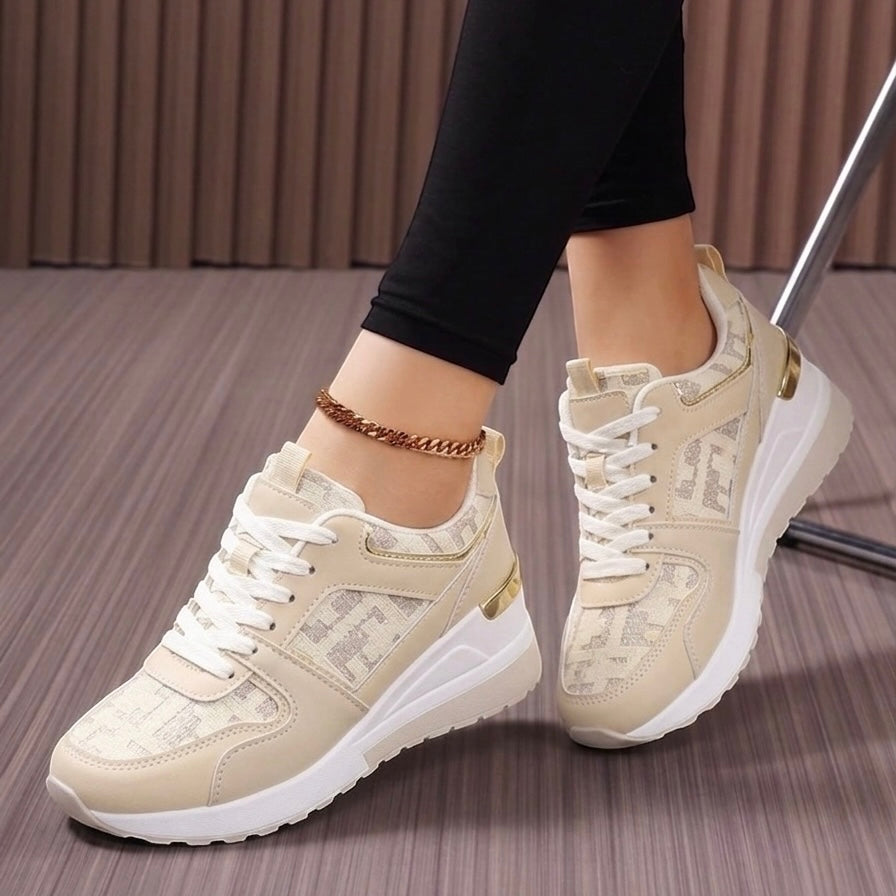 Beige sneakers with white soles worn by a person on a wooden floor.