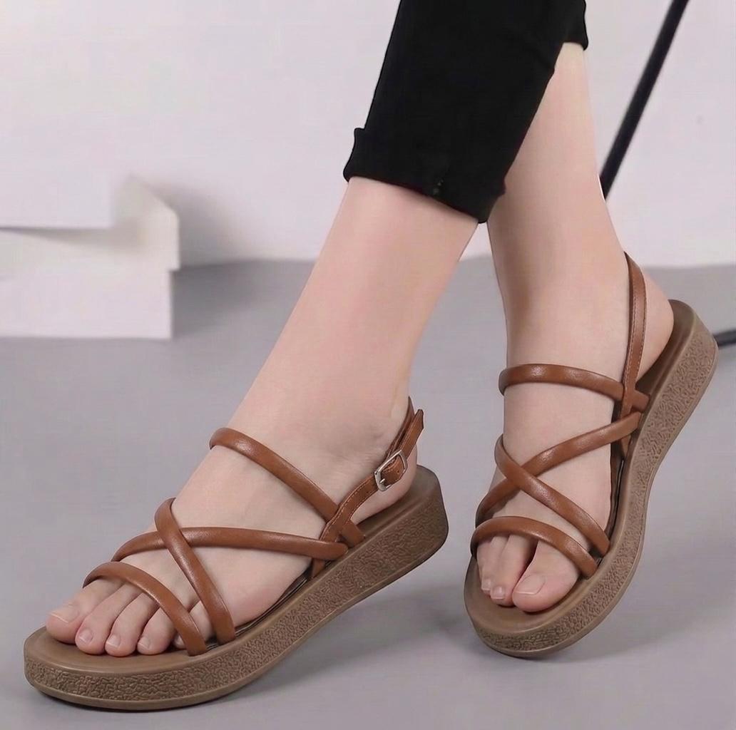 Brown sandals worn by a person on a neutral background
