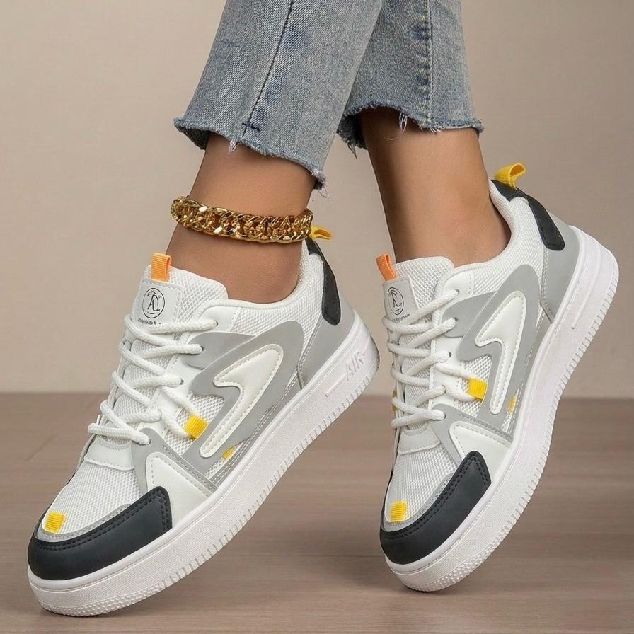 White and gray sneakers with black accents worn by a person on a neutral background